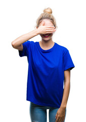 Wall Mural - Young beautiful blonde and blue eyes woman wearing blue t-shirt over isolated background smiling and laughing with hand on face covering eyes for surprise. Blind concept.