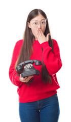 Wall Mural - Young Chinese woman over isolated background holding vintage telephone cover mouth with hand shocked with shame for mistake, expression of fear, scared in silence, secret concept