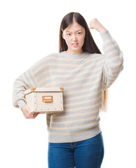 Canvas Print - Young Chinese woman over isolated background holding a box annoyed and frustrated shouting with anger, crazy and yelling with raised hand, anger concept