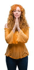 Canvas Print - Young redhead woman praying with hands together asking for forgiveness smiling confident.
