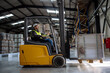 © Halfpoint - Side view of forklift in warehouse with male driver. Warehouse worker preparing products for shipmennt, delivery, checking stock in warehouse.