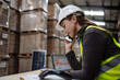 © Halfpoint - Warehouse worker checking delivery, stock in warehouse on computer, pc, while phone calling with contractor. Warehouse manager using warehouse management software, app.