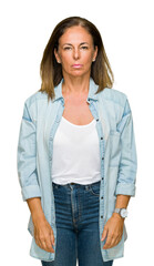 Wall Mural - Middle age adult woman wearing casual denim shirt over isolated background with serious expression on face. Simple and natural looking at the camera.