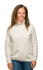 Canvas Print - Beautiful middle age adult woman wearing winter sweater over isolated background sticking tongue out happy with funny expression. Emotion concept.