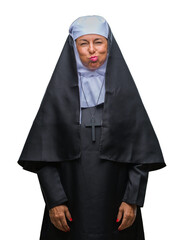 Sticker - Middle age senior christian catholic nun woman over isolated background puffing cheeks with funny face. Mouth inflated with air, crazy expression.