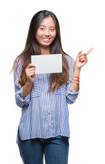 Sticker - Young asian woman holding blank card over isolated background very happy pointing with hand and finger to the side