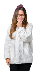 Canvas Print - Young beautiful brunette hipster woman wearing glasses and winter hat over isolated background looking confident at the camera with smile with crossed arms and hand raised on chin. Thinking positive.