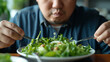 Sad overweight man eating fresh vegetable salad. Diet concept. 