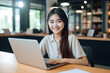 © Volodymyr - Happy Asian girl student using laptop computer in university library sitting at desk