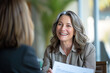 © Moritz - Confident Mature Businesswoman in Corporate Setting Engaging in Professional Consultation, Holding CV with a Pleasant Demeanor, Legal Advisor at Work, Employment Expert Discussing Career Opportunities
