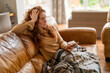 © Iryna - A Beautiful redhead woman watching TV sitting on a sofa at home, watching TV on the couch at home in the living room