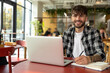 © zinkevych - Young man in plaid shirt sitting at laptop and having a video call