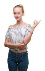 Poster - Blonde teenager woman wearing a bun very happy pointing with hand and finger to the side