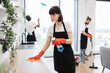 © sofiko14 - Housekeeper team in black uniform apron and put on red rubber gloves cleaning service team at home. Portrait of Caucasian young woman cleaning on table in kitchen room.
