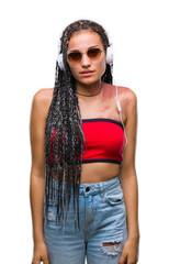 Poster - Young braided hair african american with birth mark wearing headphones over isolated background with serious expression on face. Simple and natural looking at the camera.