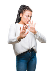 Wall Mural - Young braided hair african american girl wearing winter sweater over isolated background disgusted expression, displeased and fearful doing disgust face because aversion reaction. With hands raised.