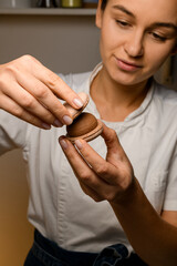 Wall Mural - Smiling female confectioner is curiously fastening the halves of macaroons