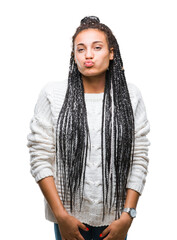 Poster - Young braided hair african american girl wearing sweater over isolated background puffing cheeks with funny face. Mouth inflated with air, crazy expression.