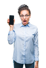 Canvas Print - Young braided hair african american business girl showing screen of smartphone over isolated background scared in shock with a surprise face, afraid and excited with fear expression