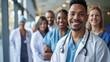© Studio Nova - Diverse group of medical professionals, with a doctor in a white lab coat and stethoscope at the forefront, smiling at the camera.