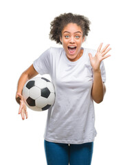 Canvas Print - Young beautiful afro american holding soccer football ball over isolated background very happy and excited, winner expression celebrating victory screaming with big smile and raised hands