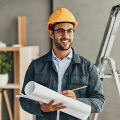 Smiling construction worker redesigning home interior with blueprint and pencil