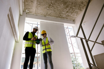 Wall Mural - Caucasian engineer and architect looking at tablet of building construction Professional event planning Inspector looking at steel structure and materials at construction site. working technology