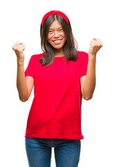 Wall Mural - Young asian woman over isolated background celebrating surprised and amazed for success with arms raised and open eyes. Winner concept.