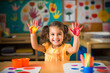 A beautiful little girl stained in multicolored paints on a pink isolated background has fun smiling. drawing rainbow. Paint on hands.
