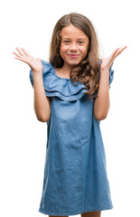 Canvas Print - Brunette hispanic girl wearing denim dress very happy and excited, winner expression celebrating victory screaming with big smile and raised hands