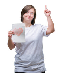 Canvas Print - Young adult woman with down syndrome holding red heart card over isolated background surprised with an idea or question pointing finger with happy face, number one