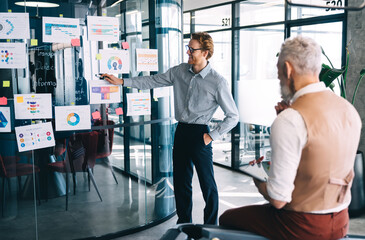 Wall Mural - Happy man presenting information to coworker in workplace