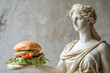 © Magryt - Ancient Greek goddess sculpture holding a burger. Female marble statue offers a cheeseburger. Fast food, overeating, bad diet, unhealthy eating habits concept, copy space. Restaurant menu mockup