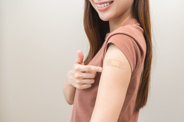 Healthcare of Covid-19, coronavirus vaccination, happy asian young woman hand pointing, showing at bandage, plaster on arm, getting vaccine immunity, giving injection influenza to protection pandemic.