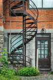 Fototapeta Na drzwi - Rusty metallic outside spiral stairs on a brick building in Montreal, Canada