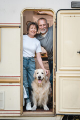 Vertical shot of senior old elderly family spouses husband and wife traveling together in camper van with golden retriever labrador domestic animal caravanning in motor home