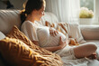 © thejokercze - Gentle dreamy woman pregnant girl sitting on comfy couch touching belly enjoying the moment