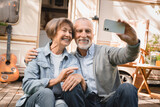 Fototapeta Londyn - Senior old elderly caucasian mature couple grandparents having videocall conversation online on cellphone while traveling by trailer motor home camper van