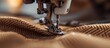 © AkuAku - Close-up of sewing machine foot with motion blur as needle moves down, focused on foot below needle tip while sewing brown fabric.