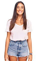 Wall Mural - Young hispanic woman wearing casual white tshirt with a happy and cool smile on face. lucky person.