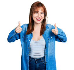 Wall Mural - Redhead young woman wearing casual denim jacket success sign doing positive gesture with hand, thumbs up smiling and happy. cheerful expression and winner gesture.