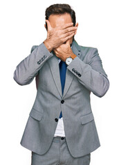 Poster - Middle age man wearing business clothes covering eyes and mouth with hands, surprised and shocked. hiding emotion