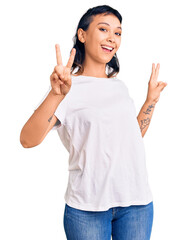 Canvas Print - Young woman wearing casual clothes smiling looking to the camera showing fingers doing victory sign. number two.