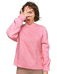 Poster - Young hispanic woman wearing casual clothes peeking in shock covering face and eyes with hand, looking through fingers with embarrassed expression.