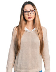 Beautiful caucasian woman wearing casual sweater and glasses relaxed with serious expression on face. simple and natural looking at the camera.