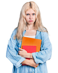 Wall Mural - Young caucasian woman holding books depressed and worry for distress, crying angry and afraid. sad expression.