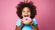 cute child excited about eating a big donut on the blue background, pink