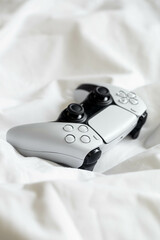 Canvas Print - Game controller, lying on white sheets of bed at home, gaming, console concep.