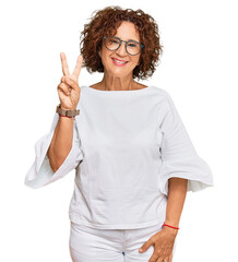 Canvas Print - Beautiful middle age mature woman wearing casual clothes and glasses showing and pointing up with fingers number two while smiling confident and happy.