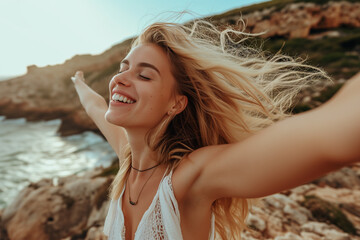 Wall Mural - Happy blonde woman with open arms and closed eyes on a rocky beach. Concept of freedom